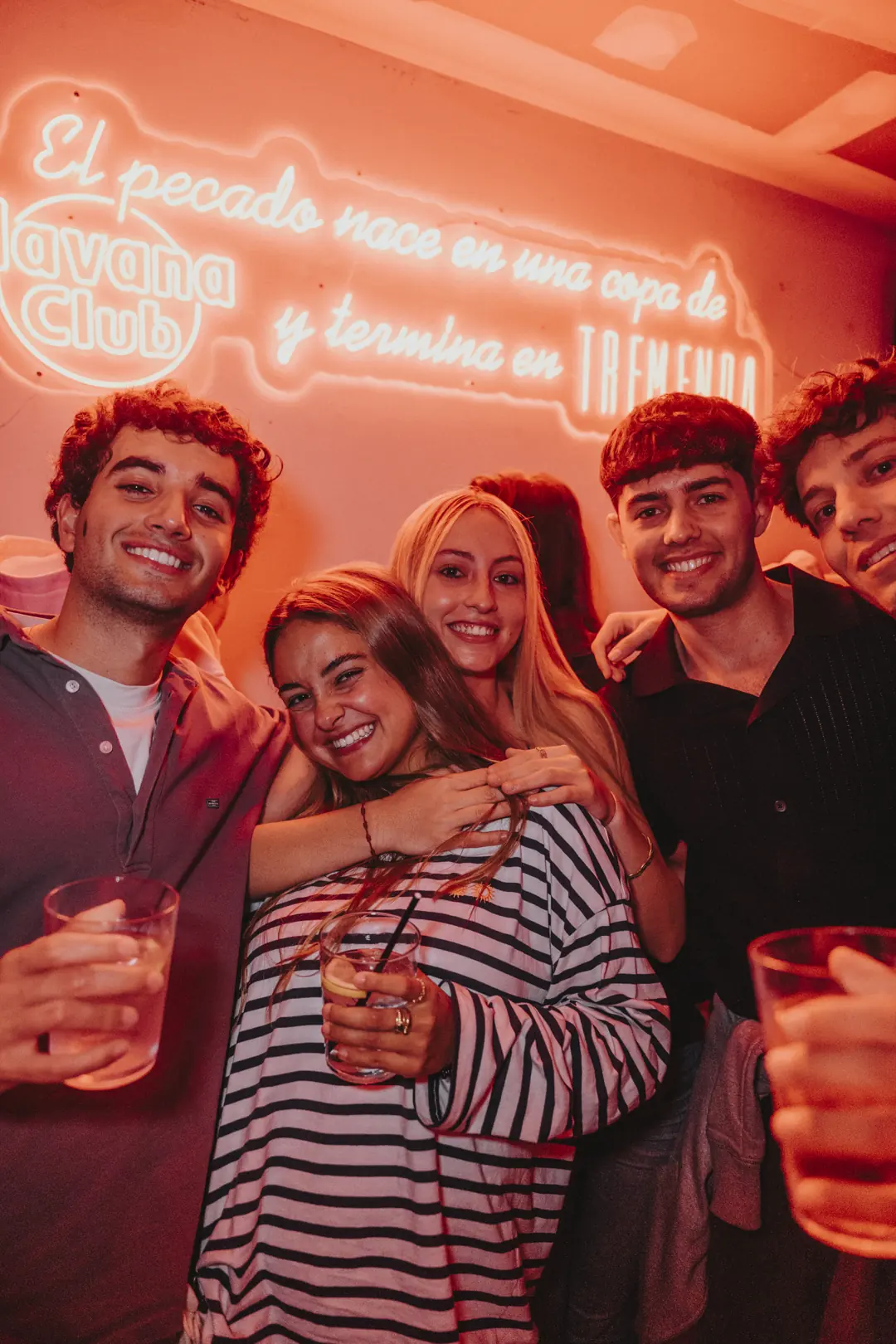 Un grupo de amigos riéndose bajo el neón de La Tremenda